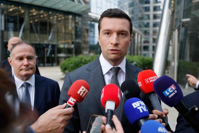 Jordan Bardella, French far-right Rassemblement National (RN) party's President, member of the European Parliament and president of the Patriots for Europe (PfE) group speaks to journalists in front of the Frontex, the European Border and Coast Guard Agency building next to Rassemblement National (RN) party member and former head of the EU's border agency Frontex Fabrice Leggeri in Warsaw, Poland on June 18, 2026. Jordan Bardella is in Warsaw to meet with leaders of Polands far right, marking the latest stop on his overseas tour aimed at strengthening his European alliances just a few months before the French presidential election. (Photo by Wojtek RADWANSKI / AFP)