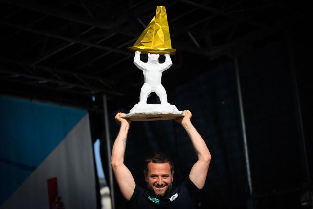 "Allagrande Mapei" Imoca monohull Italian skipper Ambrogio Beccaria celebrates whith his trophy on the podium after winning the Vendee Arctique solo sailing race, in Les Sables-d'Olonne on June 18, 2026. Beccaria won the Vendee Arctique the night of June 15, the first qualifying race for the 2028 Vendee Globe, with a close finish marked by a tribute to French offshore sailor and Vendee Globe 2024/2025 winner Charlie Dalin, who died in Quimper, western France, aged 42, from cancer, his family announced on June 11, 2026. (Photo by Loic VENANCE / AFP)