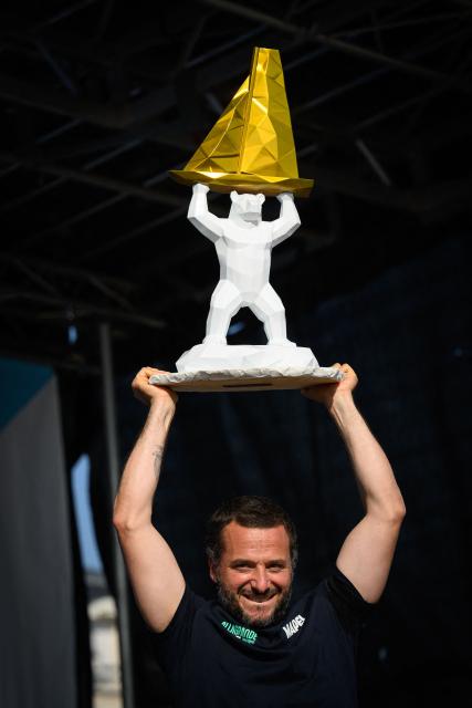 "Allagrande Mapei" Imoca monohull Italian skipper Ambrogio Beccaria celebrates whith his trophy on the podium after winning the Vendee Arctique solo sailing race, in Les Sables-d'Olonne on June 18, 2026. Beccaria won the Vendee Arctique the night of June 15, the first qualifying race for the 2028 Vendee Globe, with a close finish marked by a tribute to French offshore sailor and Vendee Globe 2024/2025 winner Charlie Dalin, who died in Quimper, western France, aged 42, from cancer, his family announced on June 11, 2026. (Photo by Loic VENANCE / AFP)