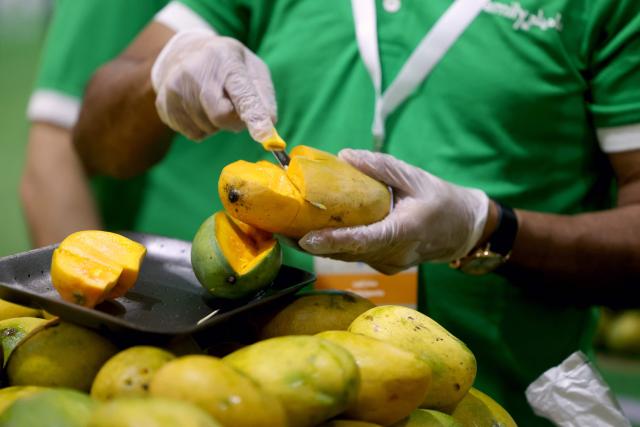 A vendor cuts mango slices at a stall during the 3rd edition of the Indian Mango Festival (Hamba Exhibition) at Souq Waqif in Doha on June 18, 2026. (Photo by Karim JAAFAR / AFP)