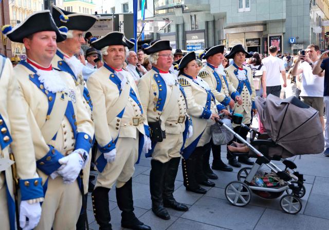 German historical military enthusiast Ann-Kathrin Werner (3rd right) is holding a stroller with her 2 years old son as she stands with her colleagues in Deutschmaster Spielmannnszug uniforms from Bad Mergentheim during the 330th anniversary celebrations of Habsburg traditional military Hoch und Deutschmeister outside of Saint Stephens cathedral on June 18, 2026 in Vienna, Austria. The "Hoch- und Deutschmeister" (K.u.K. Infanterie-Regiment Nr. 4) was one of the most prestigious and famous traditional military units of the Habsburg Empire, with origins dating back to 1696. (Photo by Joe Klamar / AFP)