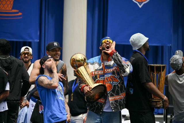 Karl-Anthony Towns (3R) #32 and Jose Alvarado (2L) #5 of the New York Knicks holds the Larry O'Brien Championship Trophy during a championship celebration and Key to the City ceremony at City Hall Plaza after a ticker-tape parade honoring the team's NBA Finals victory in New York City on June 18, 2026. (Photo by ANGELA WEISS / AFP)