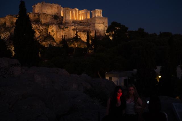 Tourists take photos on Areopagus hill overlooking the ancient Acropolis in Athens on June 18, 2026. Greece's culture ministry on June 18, 2026 said it had finished a lengthy restoration, after 220 years, of the western facade of the Parthenon in Athens, re-creating the world-famous monument's early 1800s look. The 2,500-year-old temple honouring the goddess Athena, which sits on a hill overlooking the Greek capital, is visited by more than four million people each year. (Photo by Angelos TZORTZINIS / AFP)