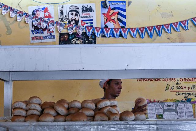 A man works in a bakery in Havana on June 18, 2026, where a photograph of late Cuban revolutionary leader Fidel Castro is displayed. (Photo by YAMIL LAGE / AFP)