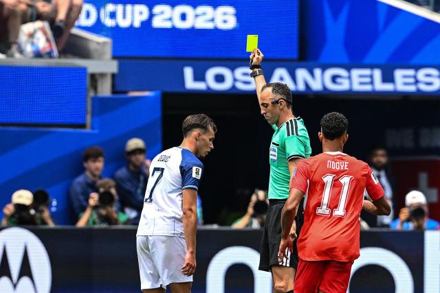 Portuguese referee Joao Pinheiro shows a yellow card to Bosnia-Herzegovina's defender #07 Amar Dedic during the 2026 World Cup Group B football match between Switzerland and Bosnia and Herzegovina at Los Angeles Stadium in Inglewood on June 18, 2026.  (Photo by Patrick T. Fallon / AFP)