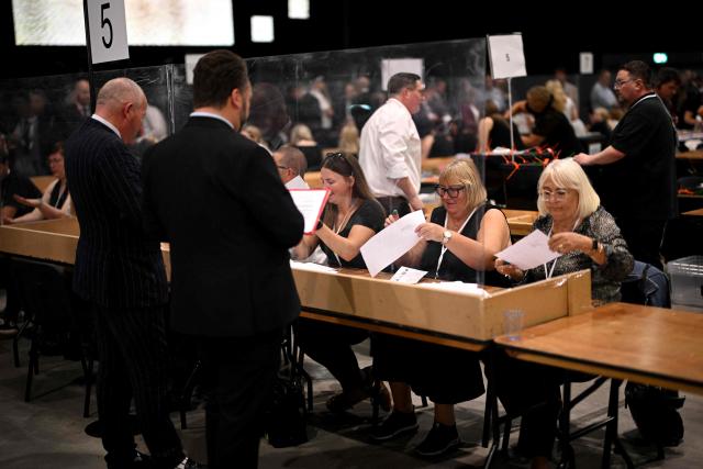 Election agents watch as votes are counted on ballot papers after polling for the Makerfield by-election closed, at the count centre venue, the Edge in Wigan, northwest England on June 18, 2026. (Photo by Oli SCARFF / AFP)