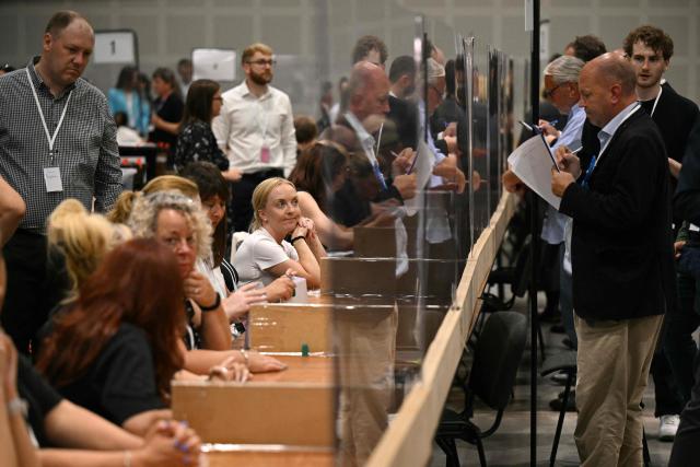 Election agents watch as votes are prepared to be counted on ballot papers after polling for the Makerfield by-election closed, at the count centre venue, the Edge in Wigan, northwest England on June 18, 2026. (Photo by Oli SCARFF / AFP)