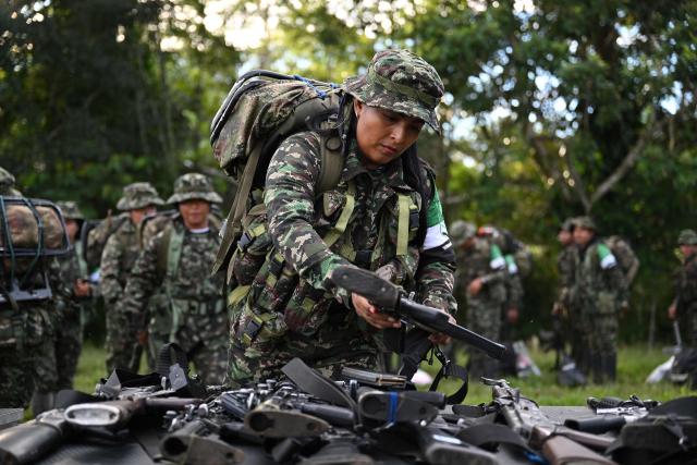 Members of the Coordinadora Nacional Ejercito Bolivariano (CNEB) guerrilla group lay down their weapons during a disarmament ceremony agreed with the Colombian government in the municipality of Valle del Guamuez, Putumayo department, Colombia on June 18, 2026. (Photo by Raul ARBOLEDA / AFP)