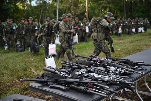 Members of the Coordinadora Nacional Ejercito Bolivariano (CNEB) guerrilla group take part in a disarmament ceremony agreed with the Colombian government in the municipality of Valle del Guamuez, Putumayo department, Colombia on June 18, 2026. (Photo by Raul ARBOLEDA / AFP)