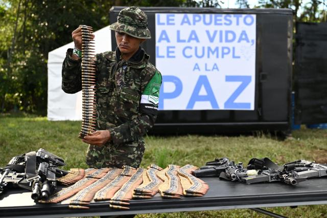 A member of the Coordinadora Nacional Ejercito Bolivariano (CNEB) guerrilla group lays down weapons during a disarmament ceremony agreed with the Colombian government in the municipality of Valle del Guamuez, Putumayo department, Colombia on June 18, 2026. (Photo by Raul ARBOLEDA / AFP)