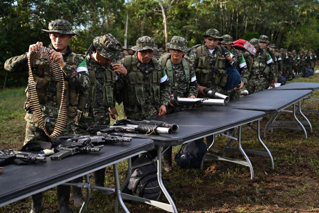 Members of the Coordinadora Nacional Ejercito Bolivariano (CNEB) guerrilla group lay down their weapons during a disarmament ceremony agreed with the Colombian government in the municipality of Valle del Guamuez, Putumayo department, Colombia on June 18, 2026. Three days before a runoff vote set to determine the continuation of the country's first leftist government, this marks a first step for the rebels to settle in a special zone where they aim to consolidate agreements with the government. (Photo by Raul ARBOLEDA / AFP)