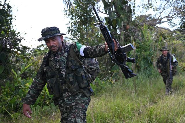 Members of the Coordinadora Nacional Ejercito Bolivariano (CNEB) guerrilla group take part in a disarmament ceremony agreed with the Colombian government in the municipality of Valle del Guamuez, Putumayo department, Colombia on June 18, 2026. Three days before a runoff vote set to determine the continuation of the country's first leftist government, this marks a first step for the rebels to settle in a special zone where they aim to consolidate agreements with the government. (Photo by Raul ARBOLEDA / AFP)