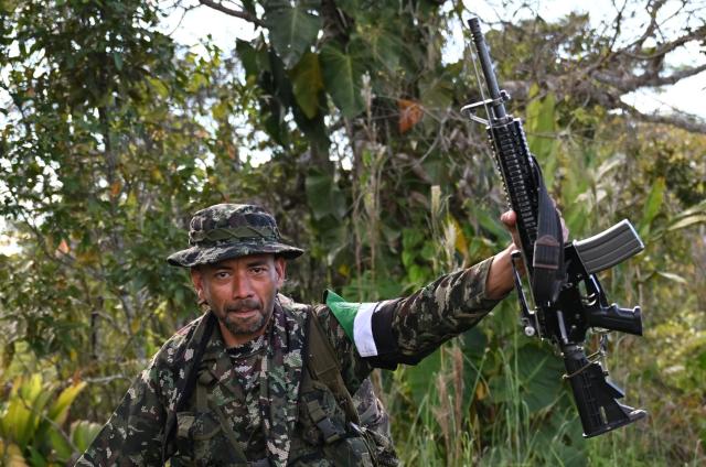A member of the Coordinadora Nacional Ejercito Bolivariano (CNEB) guerrilla group takes part in a disarmament ceremony agreed with the Colombian government in the municipality of Valle del Guamuez, Putumayo department, Colombia on June 18, 2026. Three days before a runoff vote set to determine the continuation of the country's first leftist government, this marks a first step for the rebels to settle in a special zone where they aim to consolidate agreements with the government. (Photo by Raul ARBOLEDA / AFP)