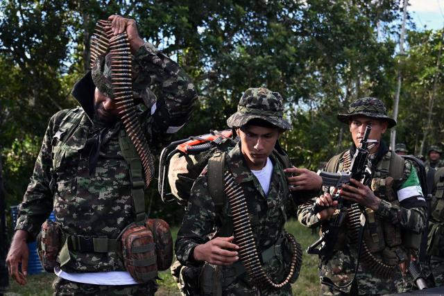 Members of the Coordinadora Nacional Ejercito Bolivariano (CNEB) guerrilla group lay down their weapons during a disarmament ceremony agreed with the Colombian government in the municipality of Valle del Guamuez, Putumayo department, Colombia on June 18, 2026. Three days before a runoff vote set to determine the continuation of the country's first leftist government, this marks a first step for the rebels to settle in a special zone where they aim to consolidate agreements with the government. (Photo by Raul ARBOLEDA / AFP)