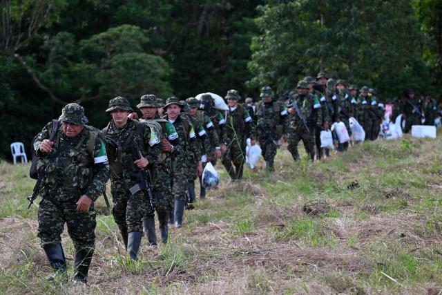 Members of the Coordinadora Nacional Ejercito Bolivariano (CNEB) guerrilla group take part in a disarmament ceremony agreed with the Colombian government in the municipality of Valle del Guamuez, Putumayo department, Colombia on June 18, 2026. Three days before a runoff vote set to determine the continuation of the country's first leftist government, this marks a first step for the rebels to settle in a special zone where they aim to consolidate agreements with the government. (Photo by Raul ARBOLEDA / AFP)