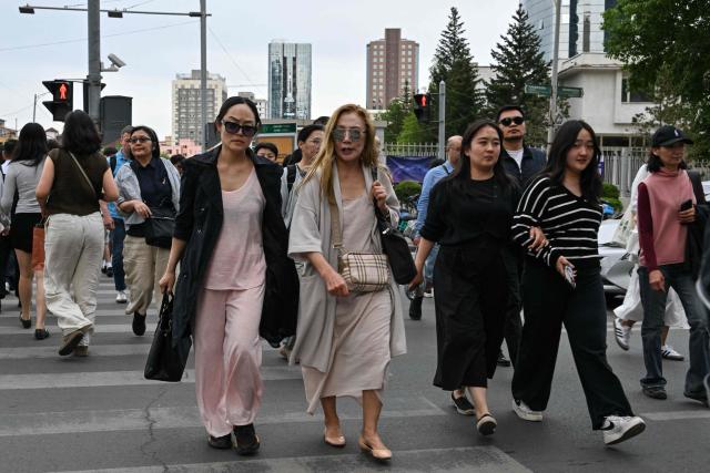 People walk across a road in Ulaanbaatar on June 18, 2026. (Photo by ADEK BERRY / AFP)