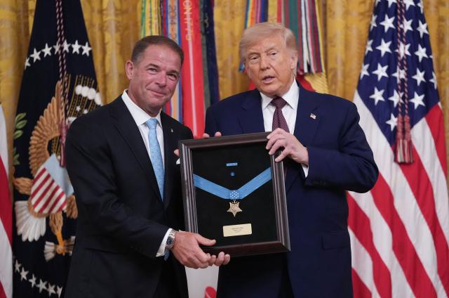 US President Donald Trump awards the Medal of Honor to US Marine Corps Colonel John W. Ripley, as his son Tom Ripley accepts the award on his behalf, during a ceremony in the East Room of the White House in Washington, DC, on June 18, 2026. (Photo by Ken Cedeno / AFP)