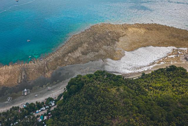 This photo taken on June 18, 2026, shows an aerial photo of the coastal uplift following an earthquake along the Pangyan Marine Sanctuary in Glan, Sarangani. A powerful earthquake that killed at least 61 people in the Philippines raised the seabed by as much as two metres (6.6 feet), exposing coral and harming marine life, the environment department said on June 14. (Photo by Ferdinandh Cabrera / AFP)