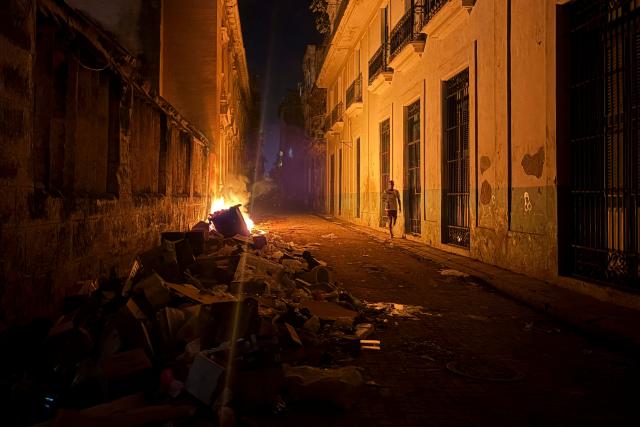 A man walks past a pile of burning garbage during a power outage in Havana on June 18, 2026. (Photo by Pablo PORCIUNCULA / AFP)