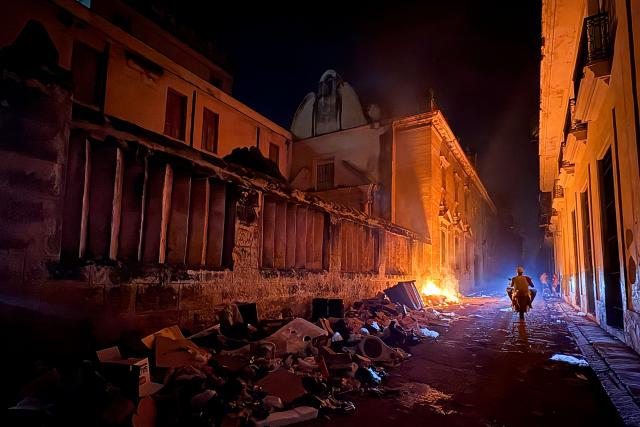 A motorcyclist rides past a pile of burning garbage during a power outage in Havana on June 18, 2026. (Photo by Pablo PORCIUNCULA / AFP)