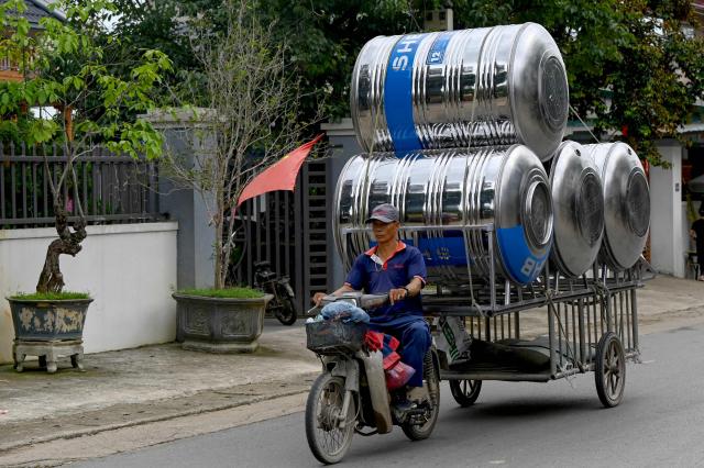 A man rides a motorbike transporting water storage tanks on a road in Hanoi on June 19, 2026. (Photo by Nhac NGUYEN / AFP)