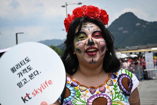 A Mexican fan celebrates after their team win in the 2026 World Cup football match against South Korea at Gwanghwamun Square in Seoul on June 19, 2026. (Photo by Jade GAO / AFP)