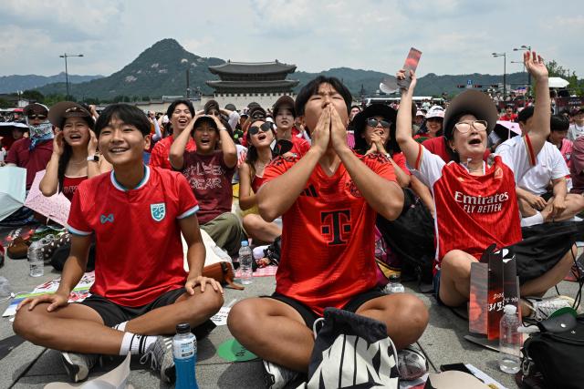 TOPSHOT - South Korean fans react as they watch the 2026 World Cup football match between South Korea and Mexico on big screens at Gwanghwamun Square in Seoul on June 19, 2026. (Photo by Jade GAO / AFP)