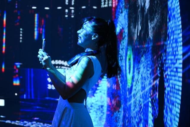 Brittany Quidang records immersive visualizations from the inaugural exhibition Machine Dreams: Rainforest are projected at DATALAND, the Museum of AI Arts, in Los Angeles, California on June 9, 2026. The squawks of macaws, the smell of wet earth after rain, and the swirl of colours will transport visitors to a Los Angeles museum to the heart of the Amazon rainforest -- or rather, an AI version of it. Data collected from those visitors  their movements, their heartbeats, and even the temperature of their skin -- will feed the computer that is creating the immersive display, using a network of sensors, including those on the wrists of ticket-holders. (Photo by Patrick T. Fallon / AFP)