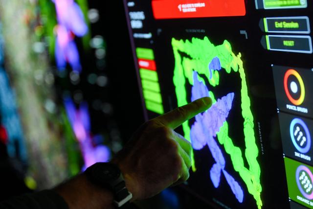 A guest touches a screen to interact with Immersive visualizations from the inaugural exhibition Machine Dreams: Rainforest are projected at DATALAND, the Museum of AI Arts, in Los Angeles, California on June 9, 2026. The squawks of macaws, the smell of wet earth after rain, and the swirl of colours will transport visitors to a Los Angeles museum to the heart of the Amazon rainforest -- or rather, an AI version of it. Data collected from those visitors  their movements, their heartbeats, and even the temperature of their skin -- will feed the computer that is creating the immersive display, using a network of sensors, including those on the wrists of ticket-holders. (Photo by Patrick T. Fallon / AFP)