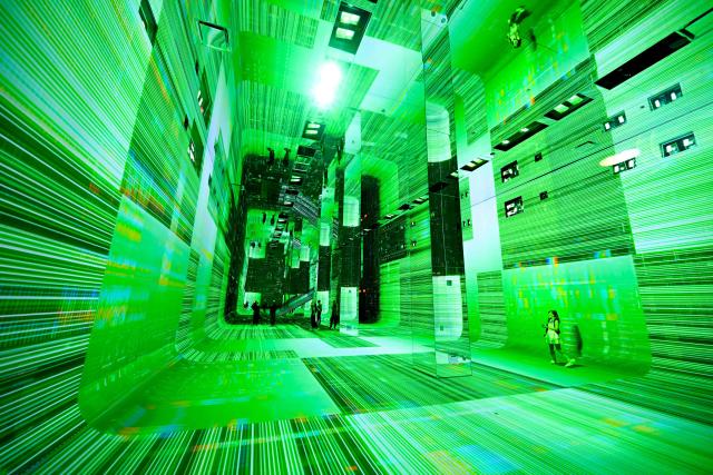 People walk through immersive visualizations from the inaugural exhibition Machine Dreams: Rainforest are projected at DATALAND, the Museum of AI Arts, in Los Angeles, California on June 9, 2026. The squawks of macaws, the smell of wet earth after rain, and the swirl of colours will transport visitors to a Los Angeles museum to the heart of the Amazon rainforest -- or rather, an AI version of it. Data collected from those visitors  their movements, their heartbeats, and even the temperature of their skin -- will feed the computer that is creating the immersive display, using a network of sensors, including those on the wrists of ticket-holders. (Photo by Patrick T. Fallon / AFP)
