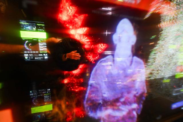 A guest touches a screen to interact with Immersive visualizations from the inaugural exhibition Machine Dreams: Rainforest are projected at DATALAND, the Museum of AI Arts, in Los Angeles, California on June 9, 2026. The squawks of macaws, the smell of wet earth after rain, and the swirl of colours will transport visitors to a Los Angeles museum to the heart of the Amazon rainforest -- or rather, an AI version of it. Data collected from those visitors  their movements, their heartbeats, and even the temperature of their skin -- will feed the computer that is creating the immersive display, using a network of sensors, including those on the wrists of ticket-holders. (Photo by Patrick T. Fallon / AFP)