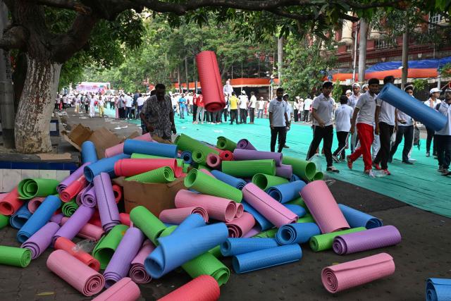 Volunteers return mats after participating in a yoga session in Kolkata on June 19, 2026. (Photo by Dibyangshu SARKAR / AFP)