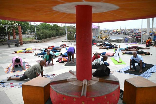 People practice yoga at the Marina beach in Chennai on June 19, 2026. (Photo by R.Satish BABU / AFP)