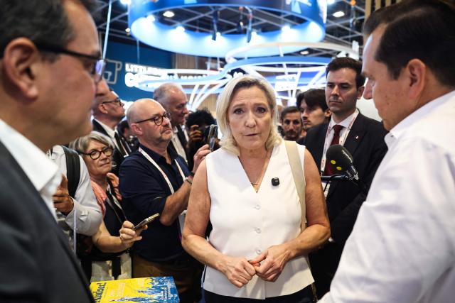 President of Rassemblement National parliamentary group Marine Le Pen (C) speaks with members of staff at the stand of French open source software editor Linagora during a visit of the VivaTech technology startups and innovation fair at the Paris Expo Porte de Versailles, in Paris on June 19, 2026. (Photo by SIMON WOHLFAHRT / AFP)