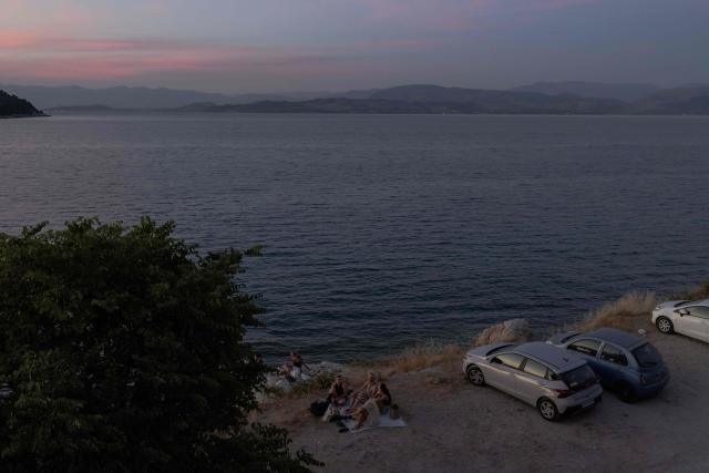 A group of people rest by the Mediterranean sea on the Greek island of Corfu, on June 14, 2026. (Photo by Roman PILIPEY / AFP)