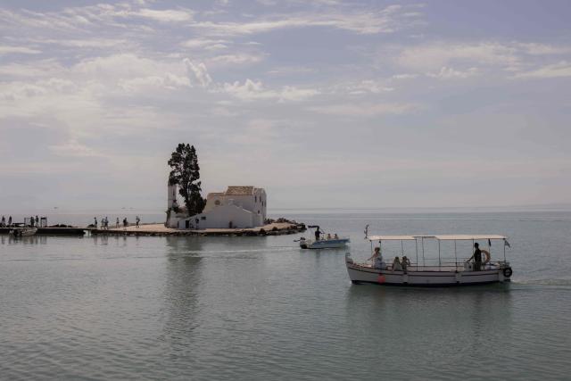 A sailor navigates a tourist boat past the Monastery of Panagia Vlacherna, on the Greek island of Corfu, on June 17, 2026. (Photo by Roman PILIPEY / AFP)