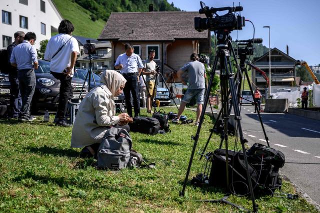 Journalists set up near an access to the Burgenstock luxury hotel complex above Lake Lucerne, where talks following up on a deal to end the Middle East conflict were scheduled to begin, on June 19, 2026. Switzerland announced on June 19, 2026 that planned talks following up on the deal to end the Middle East war had been postponed, hours after US Vice President JD Vance's departure for the Alpine country was cancelled. (Photo by Fabrice COFFRINI / AFP)