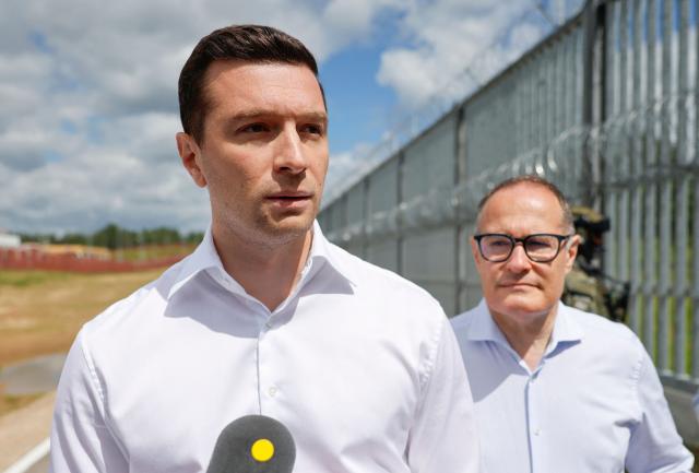 French far-right Rassemblement National (RN) party's President, member of the European Parliament and president of the Patriots for Europe (PfE) group Jordan Bardella talks to journalists as former head of the EU's border agency Frontex Fabrice Leggeri (R) looks on during a visit to Poland's border with Belarus near Kuznica, eastern Poland on June 19, 2026. Jordan Bardella is on a two day visit to poland meeting with leaders of Polands far right and touring the eastern border, marking the latest stop on his overseas tour aimed at strengthening his European alliances just a few months before the French presidential election. (Photo by Wojtek RADWANSKI / AFP)
