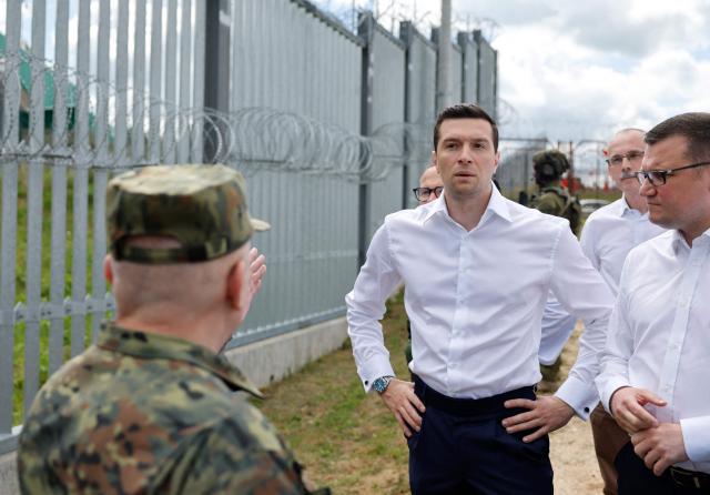 French far-right Rassemblement National (RN) party's President, member of the European Parliament and president of the Patriots for Europe (PfE) group Jordan Bardella (C) listens to Deputy Commander of the Podlaski Border Guard Unit Andrzej Stasiulewicz (L) during a visit to Poland's border with Belarus near Kuznica, eastern Poland on June 19, 2026. Jordan Bardella is on a two day visit to poland meeting with leaders of Polands far right and touring the eastern border, marking the latest stop on his overseas tour aimed at strengthening his European alliances just a few months before the French presidential election. (Photo by Wojtek RADWANSKI / AFP)