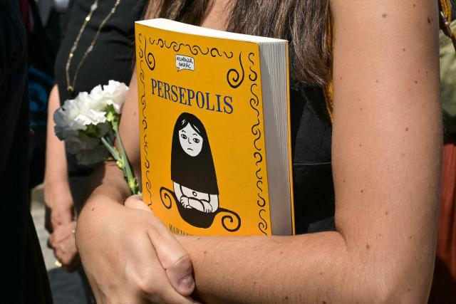 An attendee looks on carrying the comic book "Persepolis" by Franco-Iranian artist Marjane Satrapi during the funeral ceremony of the artist at the crematorium of the Pere Lachaise Cemetery in Paris on June 19, 2026. Franco-Iranian author and film director Marjane Satrapi, renowned for her graphic novel and film "Persepolis", has died aged 56, a year after the passing of "the love of her life", a member of her close circle told AFP on June 4, 2026. (Photo by JULIEN DE ROSA / AFP)
