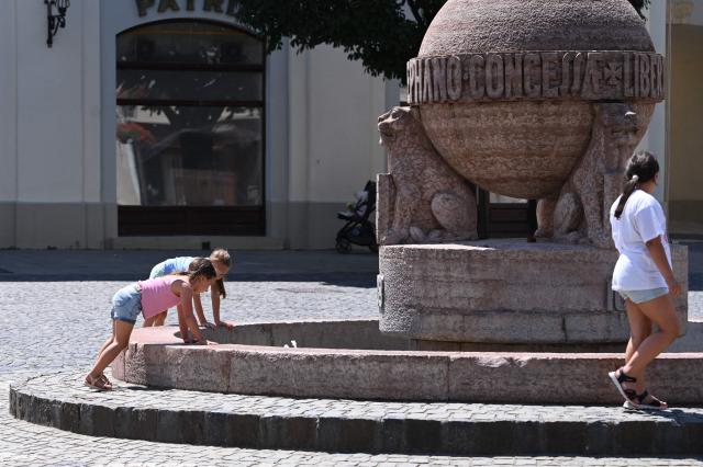 Children play at the pool of the city's symbol, The Orb monument, in Szekesfehervar, Hungary on June 19, 2026. The first major heatwave of the year is on its way, and a Level 2 heat alert will come into force from June 20, according to a statement issued on June 19 by Hungarys National Center for Public Health and Pharmacy (NNGYK) and the National Directorate General for Disaster Management. The particularly hot weather can be especially dangerous for the elderly, children, heart patients, and those with problems of the cardiovascular system. (Photo by Attila KISBENEDEK / AFP)