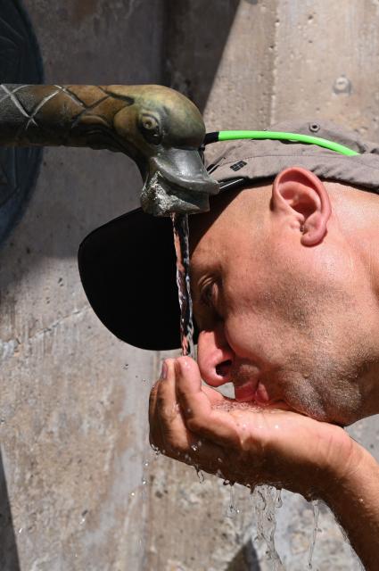 A tourist drinks from a public well during warm weather in Szekesfehervar, Hungary on June 19, 2026. The first major heatwave of the year is on its way, and a Level 2 heat alert will come into force from June 20, according to a statement issued on June 19 by Hungarys National Center for Public Health and Pharmacy (NNGYK) and the National Directorate General for Disaster Management. The particularly hot weather can be especially dangerous for the elderly, children, heart patients, and those with problems of the cardiovascular system. (Photo by Attila KISBENEDEK / AFP)