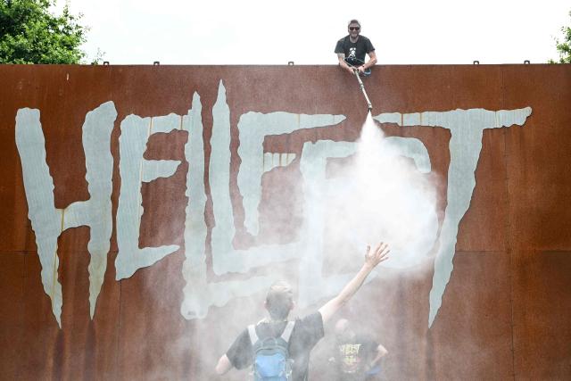 A member of the Hellfest festival crew sprays water to cool off festival goers during the 19th edition of Hellfest rock and heavy metal festival, in Clisson, western France, on June 19, 2026. (Photo by Sebastien Salom-Gomis / AFP)