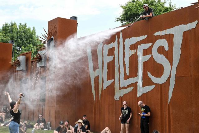 A member of the Hellfest festival crew sprays water to cool off festival goers during the 19th edition of Hellfest rock and heavy metal festival, in Clisson, western France, on June 19, 2026. (Photo by Sebastien Salom-Gomis / AFP)