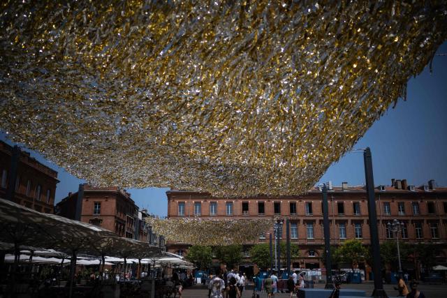 People walk through the Capitole square covered by an installation to provide shade, in Toulouse on June 19, 2026. A heatwave hits France and is set to continue for several days with temperatures expected to reach up to 40°C in some areas on June 21, the first day of summer. (Photo by Lionel BONAVENTURE / AFP)