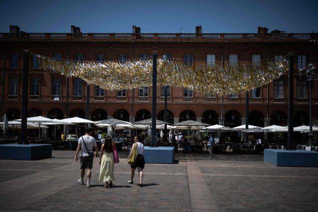 People walk through the Capitole square covered by an installation to provide shade, in Toulouse on June 19, 2026. A heatwave hits France and is set to continue for several days with temperatures expected to reach up to 40°C in some areas on June 21, the first day of summer. (Photo by Lionel BONAVENTURE / AFP)