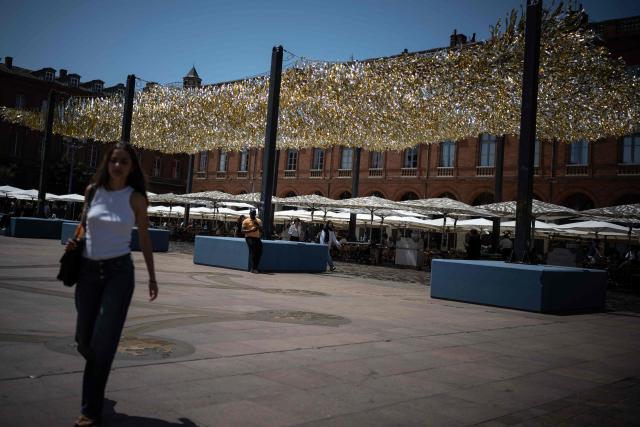 People walk through the Capitole square covered by an installation to provide shade, in Toulouse on June 19, 2026. A heatwave hits France and is set to continue for several days with temperatures expected to reach up to 40°C in some areas on June 21, the first day of summer. (Photo by Lionel BONAVENTURE / AFP)