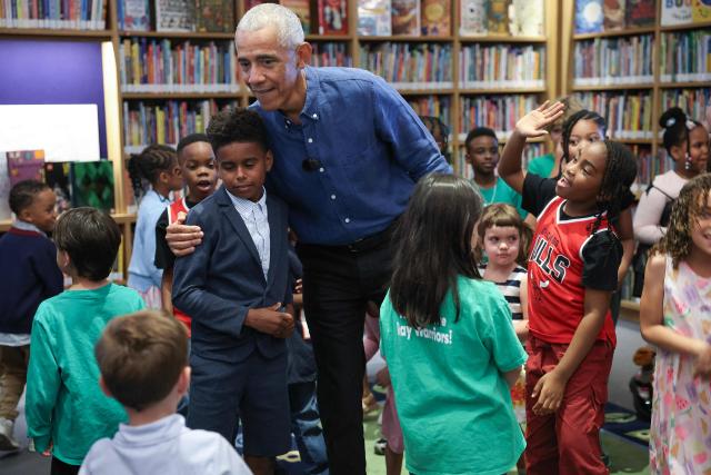 Former US President Barack Obama embraces school children after reading to them at the Barack Obama Presidential Center in John Lewis Plaza on June 19, 2026 in Chicago, Illinois. This is the first day the Barack Obama Presidential Center is open to the public. (Photo by Win McNamee / POOL / AFP)