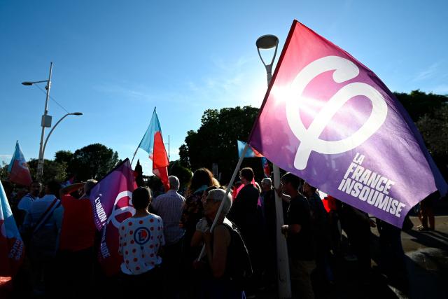 (FILES) A protester holds a flag of left wing party La France Insoumise (LFI) as they take part in a rally against the political and cultural policies of Rassemblement National's mayor Nicolas Meizonnet, who cancelled the city's jazz festival, in Vauvert, southern France, on May 20, 2026. The Paris Administrative Court on Friday suspended the police prefect's decision to ban a concert by the La France Insoumise (LFI) party scheduled to take place at Place de la République during the Fête de la Musique Festival. (Photo by Sylvain THOMAS / AFP)