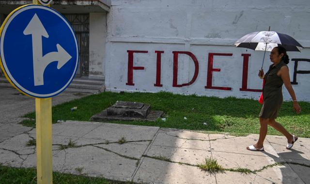A woman walks past a wall reading "Fidel forever", referring to late Cuba's President Fidel Castro in Havana on June 19, 2026. Nearly 70 years after Fidel Castro's 1959 revolution, communist-run Cuba has adopted a sweeping package of free-market reforms aimed at extricating the country from a deep crisis. (Photo by YAMIL LAGE / AFP)